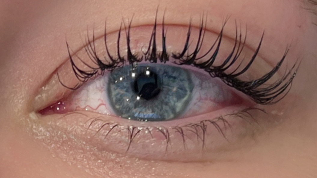 Nahaufnahme eines blauen Auges mit langen, dunklen Wimpern und lebendigen Details.