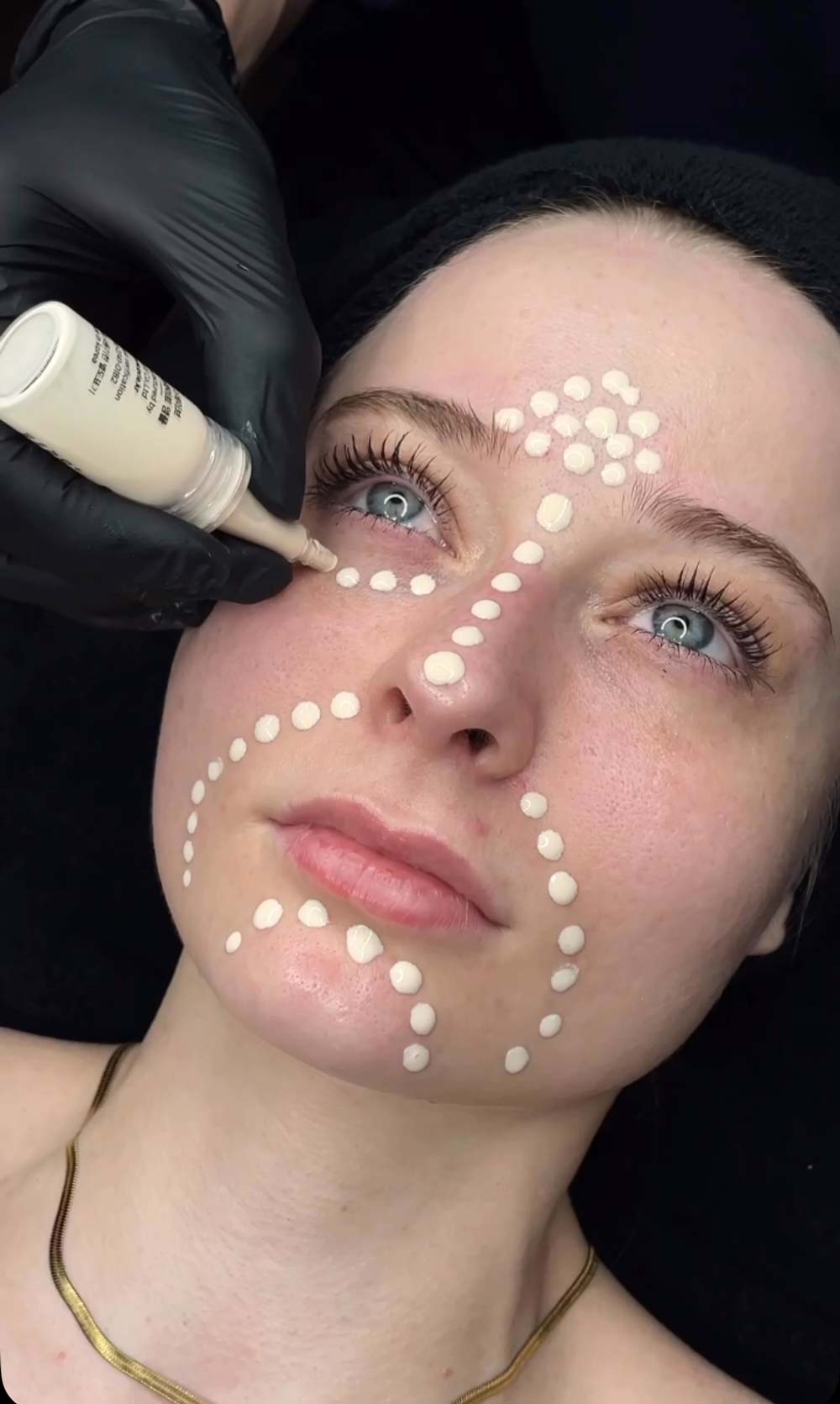 Person erhält mit Punktmuster-Make-up; ernster Ausdruck, helle Haut; schwarzer Hintergrund.
