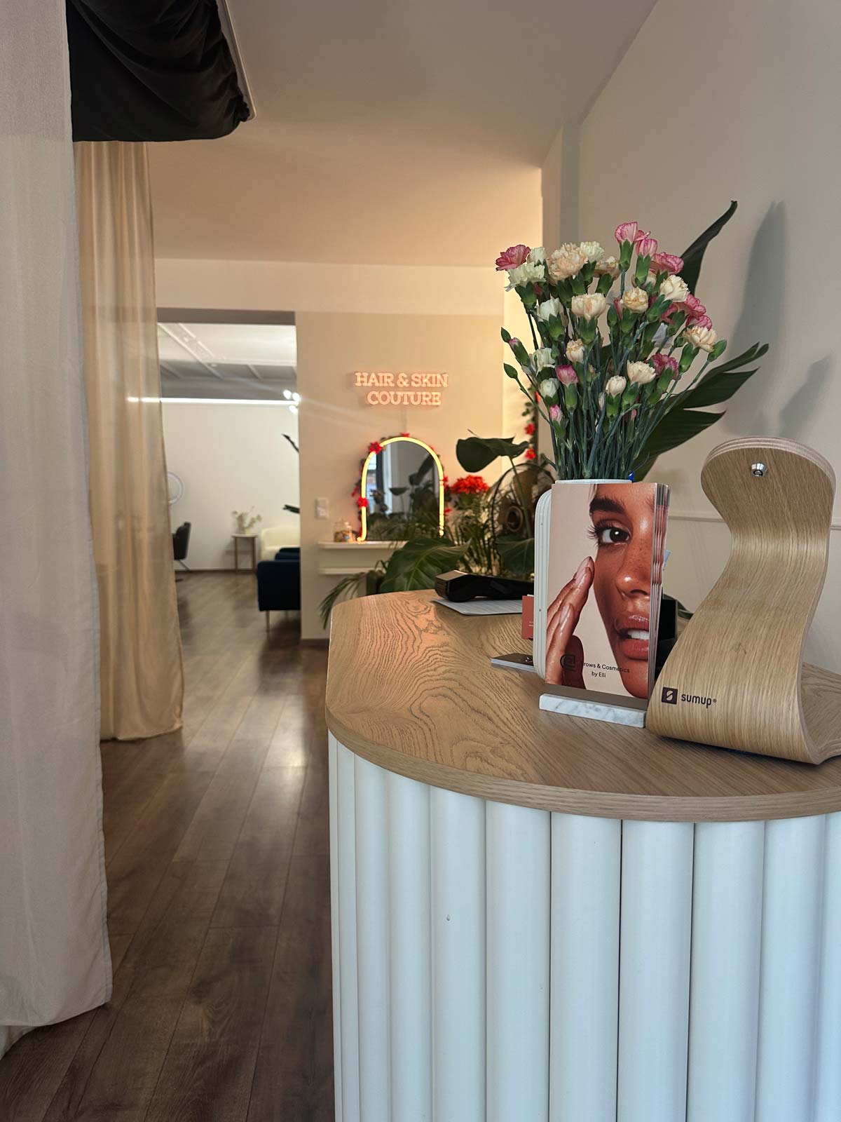 Empfangstresen mit Blumen, Holzdekoration, Broschüre und Spiegel im Hintergrund.